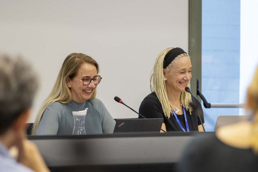Two women sitting in a podium and smilling