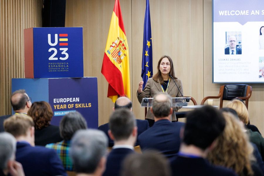 A woman at the podium presenting, banners, audience